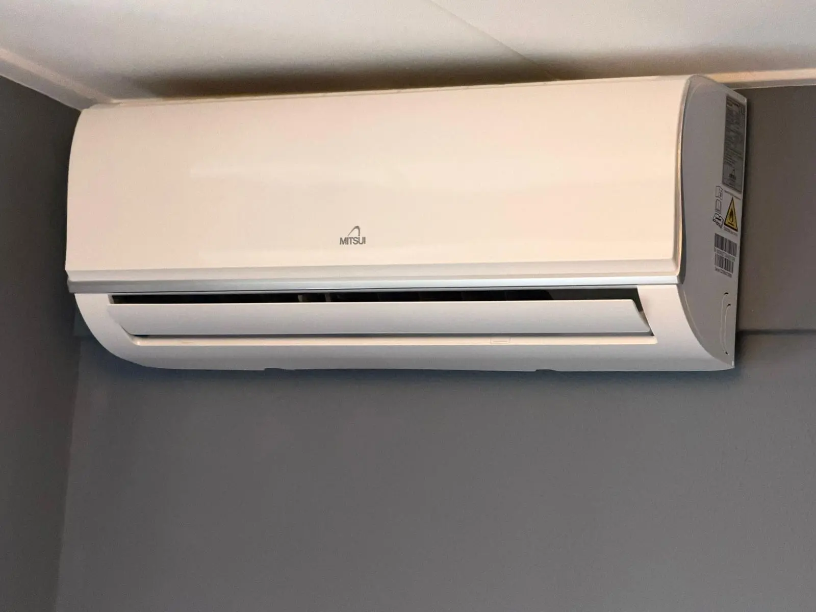Witte Mitsui airco binnenunit strak tegen het plafond gemonteerd in een woonkamer