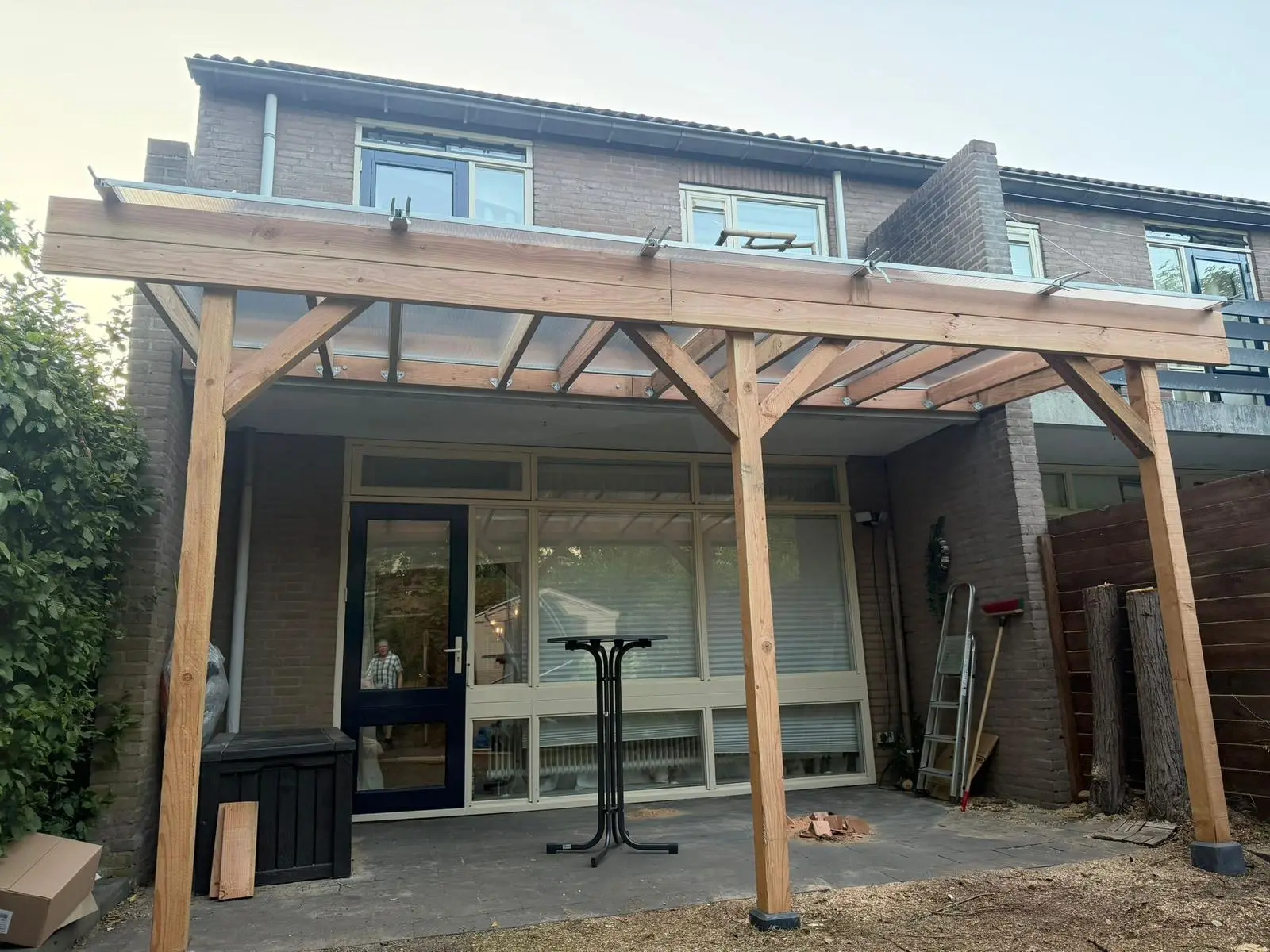 Door Compleet & Duurzaam gebouwde houten veranda met lichtdoorlatend dak tegen de achtergevel van een woning